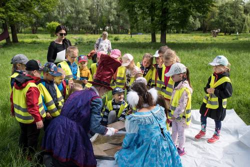 Zdjęcie przedstawia wydarzenie zorganizowane z okazji Dnia Dziecka w 2021 roku. Na zdjęciu widać animatorów oraz dzieci w parku w centrum miasta Pruszcz Gdański.